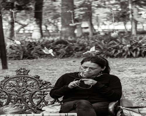 Mexican woman smiling and relaxing on a park bench during a sunny day